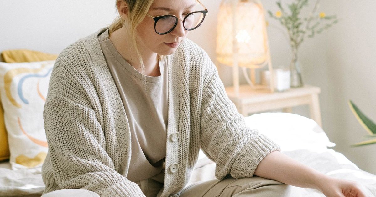 Woman sitting on a bed using a laptop to search online